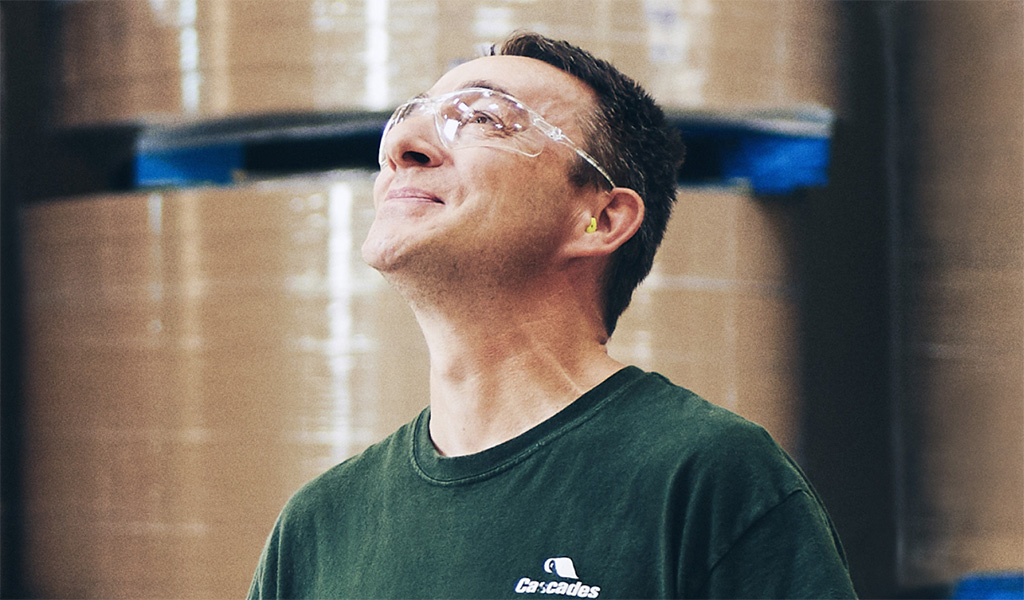 Employés en usine manipulant du carton ondulé illustrant l’expertise de Cascades en emballage durable