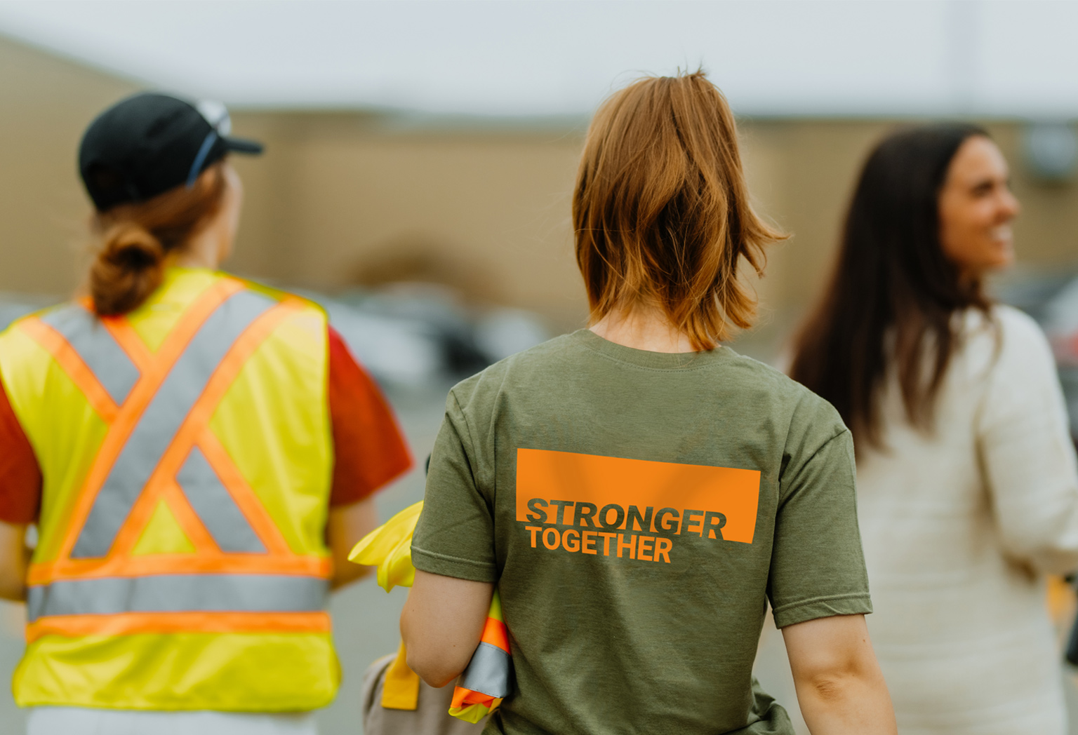 Three employees walk with their backs to each other on a t-shirt that reads "More Ford Together".