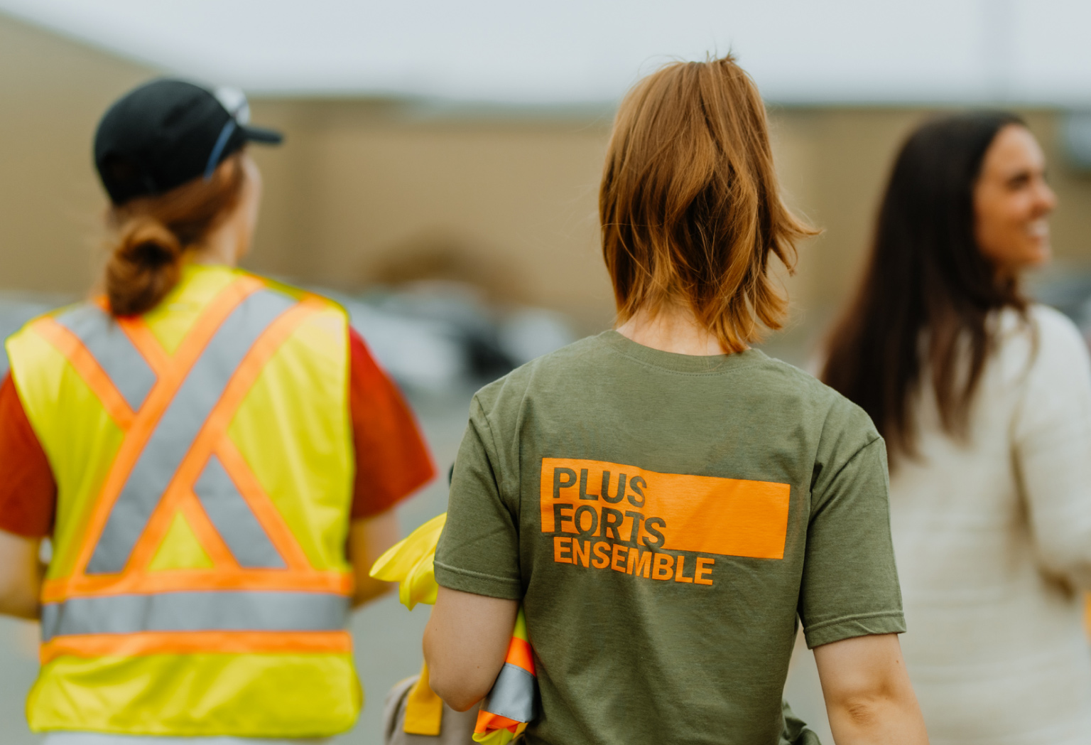 Trois employées marche de dos sur une t-shirt écrit plus ford ensemble