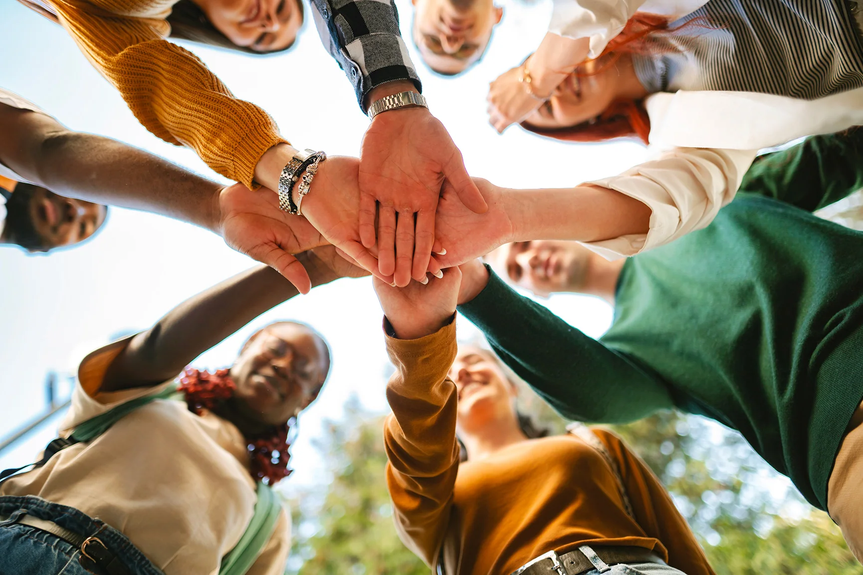Employés aux profils divers réunissant leurs mains pour symboliser la collaboration, l’inclusion et l’engagement collectif.