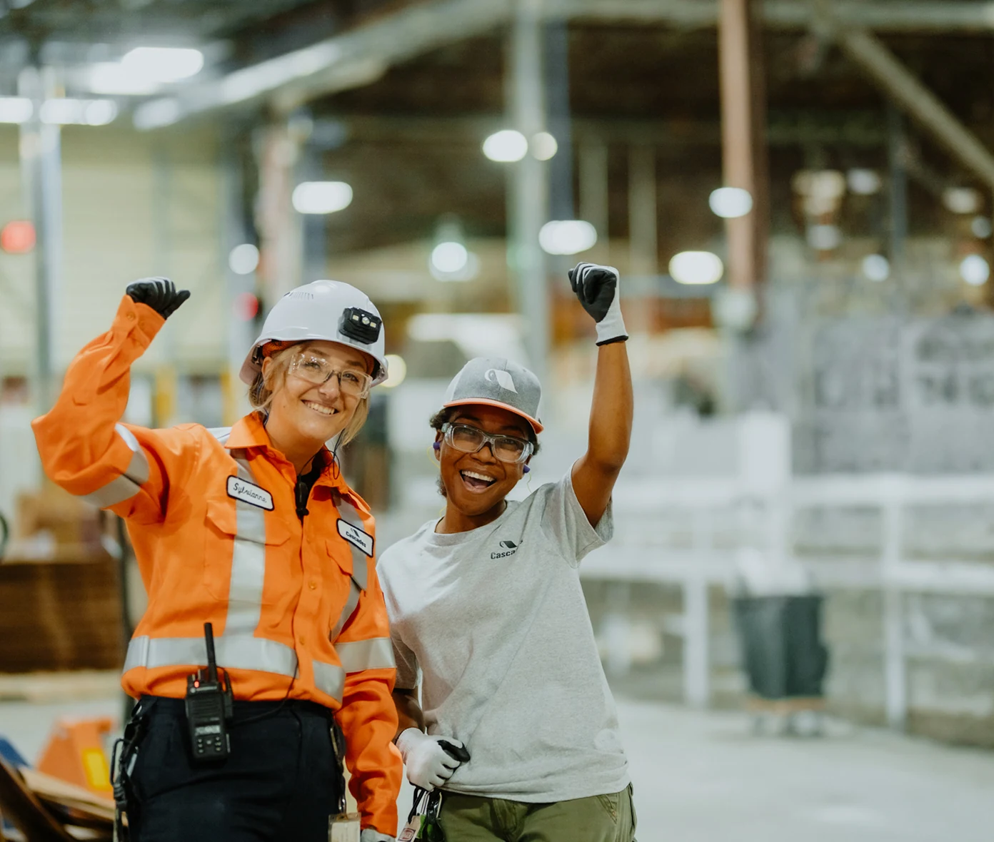 Deux employées en usine portant des équipements de sécurité dans un environnement manufacturier moderne et sécuritaire.