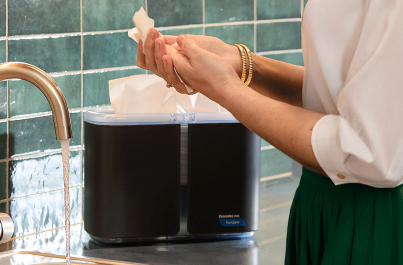 Personne qui s’essuie les mains avec l'essuie-mains à plis multiples de qualité supérieure Cascades PRO Perform® à côté d'un lavabo